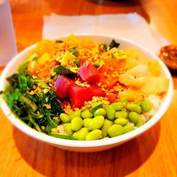 Poke bowl (half rice/ half green, salmon/tuna, Wakame, edamame, mango, cucumber,, pineapple, ginger sauce on the side.