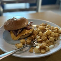 Bacon, egg and cheese on a brioche with potatoes and onion.