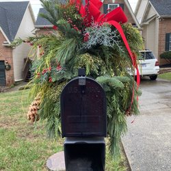 Ellenburg Landscaping & Nursey - Mixed greens, red berries and giant pine cones topped by a red velvet bow.