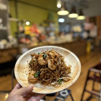 Reunion Malaysian Cafe + Kitchen - a person holding a plate of noodles - Malaysian Near Me - Kirkland, Washington