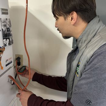 Certified-Environmental - Jackson performing a moisture test behind a refrigerator. - Home Inspectors Near Me Certified-Environmental - Jackson performing a moisture test behind a refrigerator. - Home Inspectors Near Me