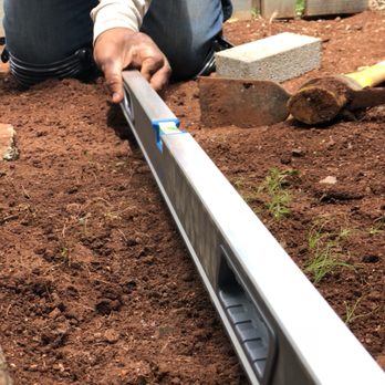 RD Landscaping - a man using a leveling tool to level a garden bed - Landscaping Near Me RD Landscaping - a man using a leveling tool to level a garden bed - Landscaping Near Me