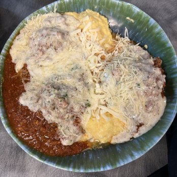 Saluti’s - A dish featuring melted cheese, ground meat, and sauce on a green plate, with mashed potatoes and shredded cheese. - Italian Near Me - Jackson, California