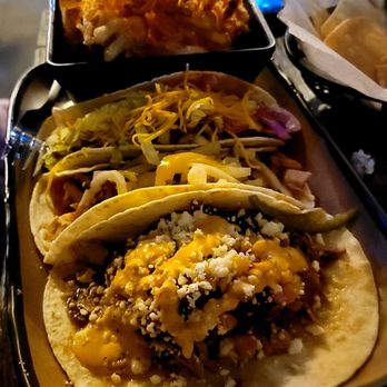 Lowkey Taco - A tray holds three tacos with various toppings and a side of fried food in a small container, likely at a restaurant or food stand. - Tacos Near Me - Pittsburgh, Pennsylvania