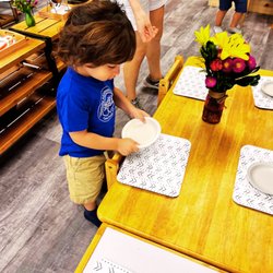 Dynamite Montessori Academy - Child setting the table for classmates during lunch. Practical life exercises instill care for self, others and the environment.