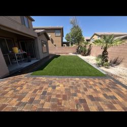 Leo’s Landscape - Design of paver with a patch of synthetic grass surrounded with a border of darker pavers.