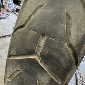 Thunderbird Harley-Davidson - Manufacturing defective cracks in HD Dunlop tire. - A motorcycle tire shows cracks and possible manufacturing defects, with tools and workshop items visible in the background. - Motorcycle Dealers Near Me - Albuquerque, New Mexico