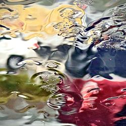 River Pub - A red car and a white car going opposite directions on Main Street as seen through a wet sheet of glass while it still rains !