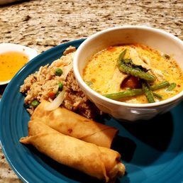 a bowl of soup and two spring rolls on a blue plate