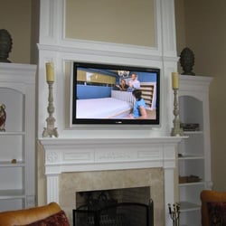 Dynamic Audio & Video - This great room TV was mounted above a wood burning fireplace. All source components are on shelves to the right.