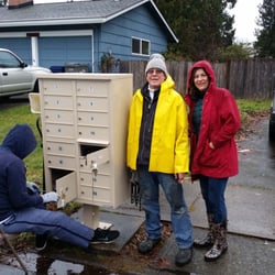 Locking Mailbox Installers - The business owners next to a new mailbox they installed in south Auburn, Washington. USPS person is changing the access locks.