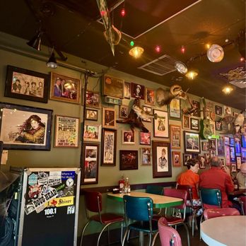 Evangeline Café - Loved the walls! - Evangeline Café's interior features a wall filled with framed photos, artwork, and mounted animal skulls, with colorful string lights and vintage decor. - Cajun/Creole Near Me - Austin, Texas
