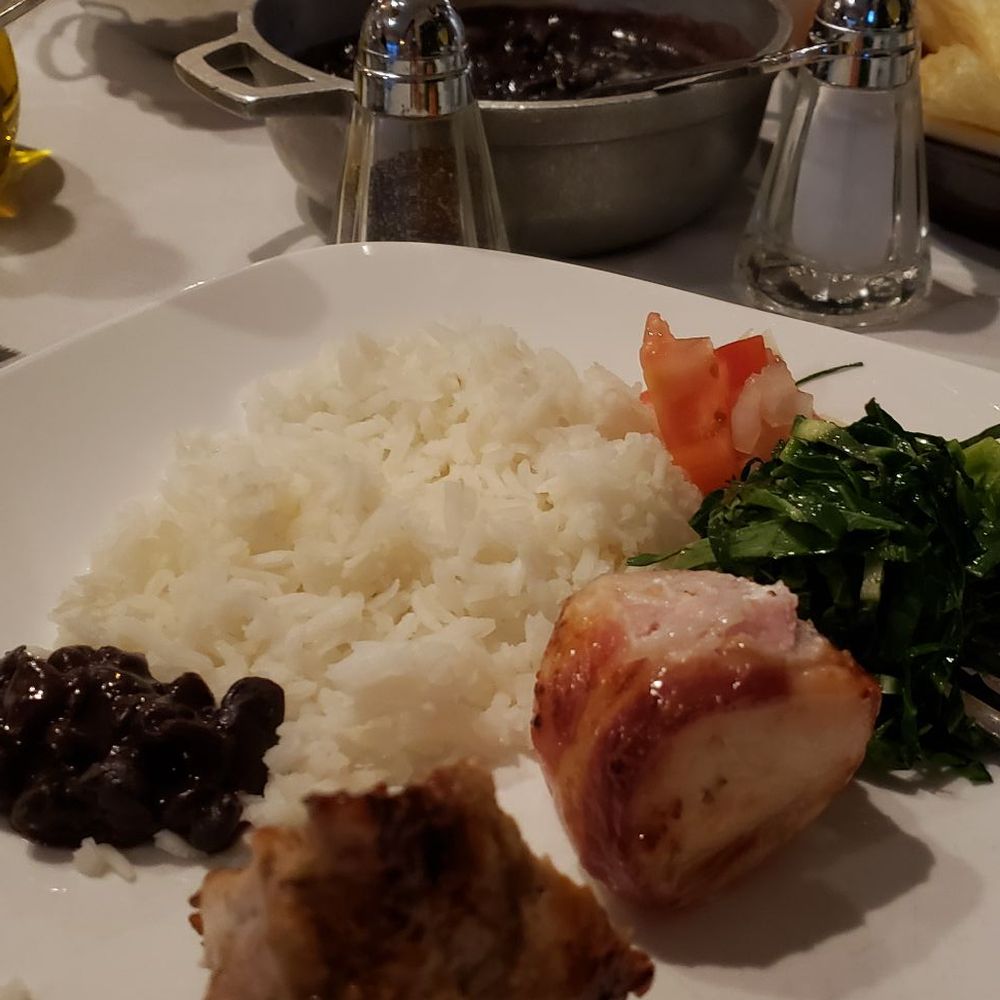Bacon-wrapped chicken and pork with arroz, black beans, homemade chips, yucca fries and plantains, pico, greens