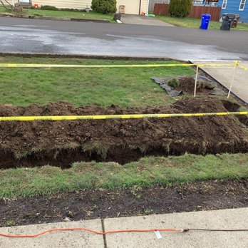 Drainage Masters - a hole in the ground with a yellow caution tape - Plumbing Near Me - Battle Ground, Washington