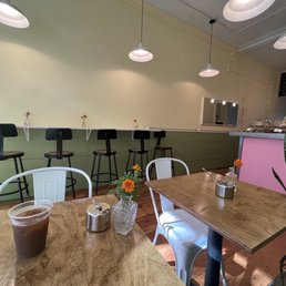 Interior with green and pink paneling, tables set with small orange flowers, and cold brew