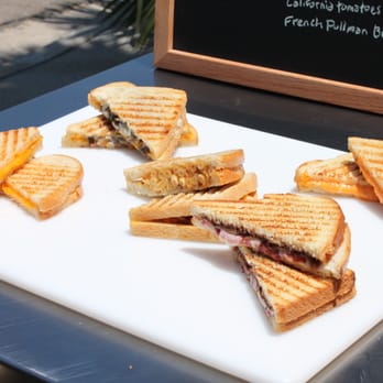Cheesy Amigos - a cut in half sandwich on a cutting board - New American Near Me Cheesy Amigos - a cut in half sandwich on a cutting board - New American Near Me