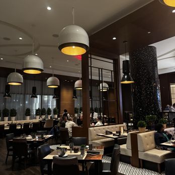 David's - A restaurant interior featuring pendant lights, dining tables, and seating arrangements with patrons dining and socializing. - New American Near Me - Hanover, Maryland