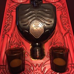 a black bottle and two shot glasses a black bottle and two shot glasses
