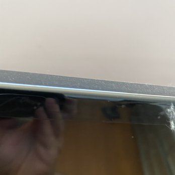 Elevated Cleaners - Top of TV - The image shows a reflective black surface with a beige wall in the background, and a partial reflection of a hand holding a device. - Home Cleaning Near Me