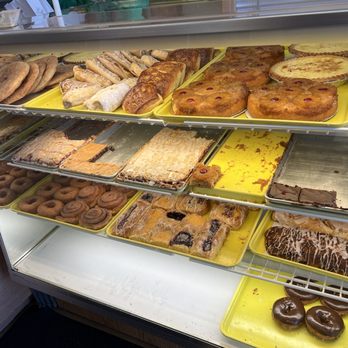 Allegretti's Bakery - Baked goods - A bakery display case contains various baked goods such as cookies, pastries, and cakes arranged on yellow trays. - Bakeries Near Me - Norridge, Illinois
