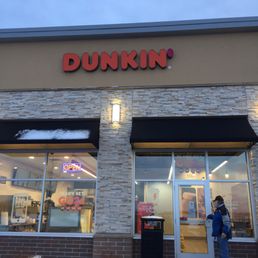  a person standing outside of a dunkin donuts store