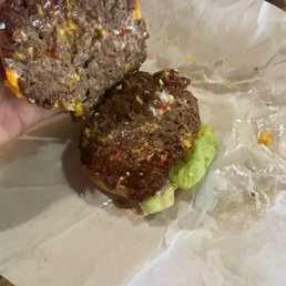 a hand holding a hamburger with a bite taken out of it