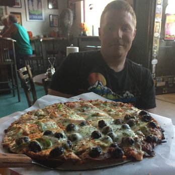 Village Idiot - Somebody can't wait to sink their teeth into the blissful cheesiness of Village Idiot pizza. - Bars Near Me - Maumee, Ohio Village Idiot - Somebody can't wait to sink their teeth into the blissful cheesiness of Village Idiot pizza. - Bars Near Me - Maumee, Ohio