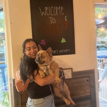 Passport Winery - a woman holding a dog in her arms - Wine Tasting Room Near Me - La Verne, California Passport Winery - a woman holding a dog in her arms - Wine Tasting Room Near Me - La Verne, California