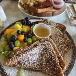 French Toast with a side of fresh fruit across from a breakfast platter