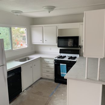 Var-City Contracting - a kitchen with white cabinets and black appliances - General Contractors Near Me Var-City Contracting - a kitchen with white cabinets and black appliances - General Contractors Near Me