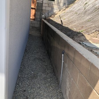 Rudy Landscape - Gravel between garage and back slope.  Note the PVC running down wall to run wire to controller as described in the review. - Landscaping Near Me