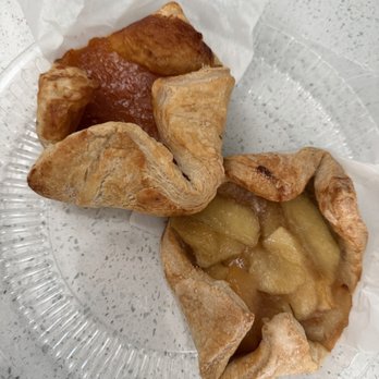 Mazzetti's Bakery - Apple and Apricot popover - Two pastries with fruit fillings are placed on a clear plastic plate with white paper lining, on a speckled countertop. - Bakeries Near Me - Pacifica, California