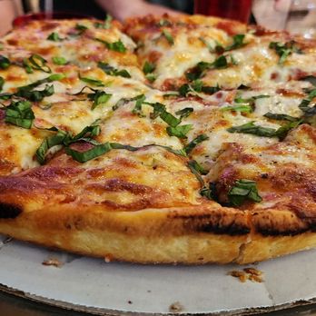 Crave Pizza  -  person cutting into a pizza - Pizza Near Me - Mesa, Arizona