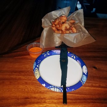 Firefly - Fried shrimp served in a paper-lined basket with a small cup of orange dipping sauce on a wooden table. - Cocktail Bars Near Me - Flushing, New York
