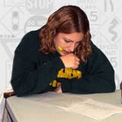 Easy Method Driving School - Hybrid student focused in the classroom, calmly taking a written test that reinforces safe‑driving knowledge before in-car (6/6) training.