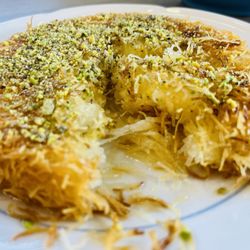 Kabsa  The Ultimate Cuisine - Cheese knaffeh close up with gooey cheese, phyllo shreds and ground pistachio topiping