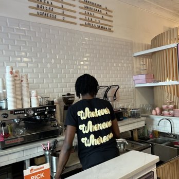 Hibiscus Brew - A person with short dreadlocks is working behind a coffee bar in a café, with a menu on the wall and coffee-making equipment. - Cafes Near Me - Brooklyn, New York