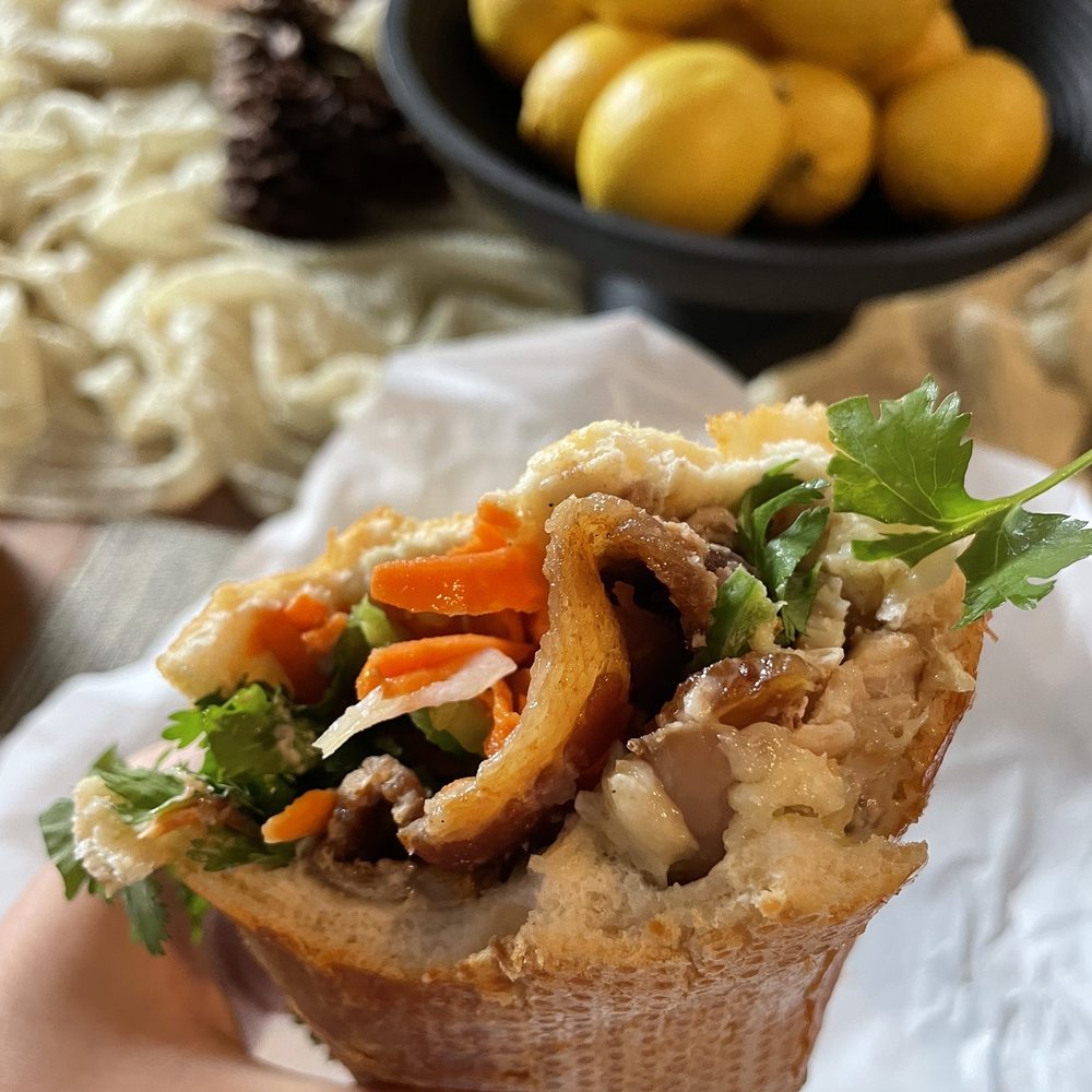 Vietlicious - a person holding a sandwich with meat and vegetables - Vietnamese Near Me - Seattle, Washington Vietlicious - a person holding a sandwich with meat and vegetables - Vietnamese Near Me - Seattle, Washington