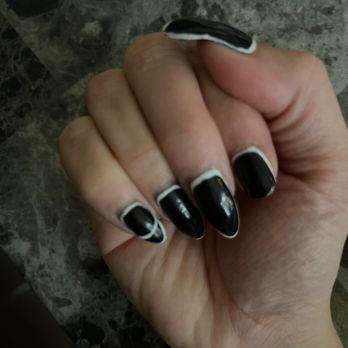 STUDIO NAILS & LASHES - A person's hand displays black nails with white accents, set against a dark, marbled background. - Nail Salons Near Me - El Paso, Texas