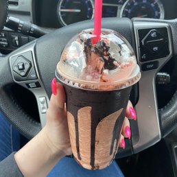 a hand holding a chocolate milkshake