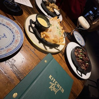 Kitchen and Rail - A dining table set with plates of food, drinks, and a menu from Kitchen and Rail, a restaurant offering eclectic craft dining. - Bars Near Me - Eagan, Minnesota