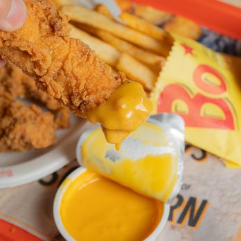 Bojangles - a person dipping a piece of fried chicken into a bowl of sauce - Fast Food Near Me - Euless, Texas