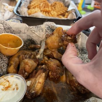Dick's Wings SR16 St Augustine FL - a hand grabbing a piece of chicken wings - Chicken Wings Near Me - St. Augustine, Florida
