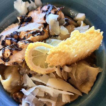 Desert Bistro - Handmade pasta - A bowl containing grilled fish, lemon slices, cheese shavings, and pasta, served in a restaurant setting. - New American Near Me - Moab, Utah