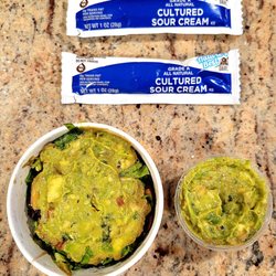 El Fresco - Guacamole with lettuce, tomatoes, olives, and cilantro on the left. Fresh guacamole on the right. Sour cream packets above.