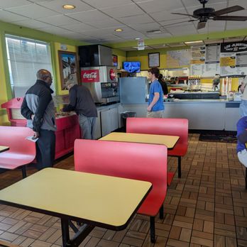 Los Jilbertos - Interior - Inside Los Jilbertos, a Mexican restaurant, with customers ordering at the counter and a woman eating at a table, featuring bright yellow walls and a menu board. - Mexican Near Me - Grand Junction, Colorado