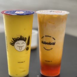 Mango Smoothie - Two bubble tea drinks in plastic cups with colorful toppings and branding from Hi Boba, featuring a yellow mango smoothie and a mixed fruit tea.