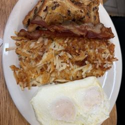 Hash-browns, bacon, over easy eggs and raisin toast