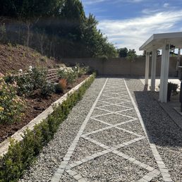 a gravel path with a pergolated area in the background