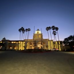 the front of a building with palm trees in the foreground
